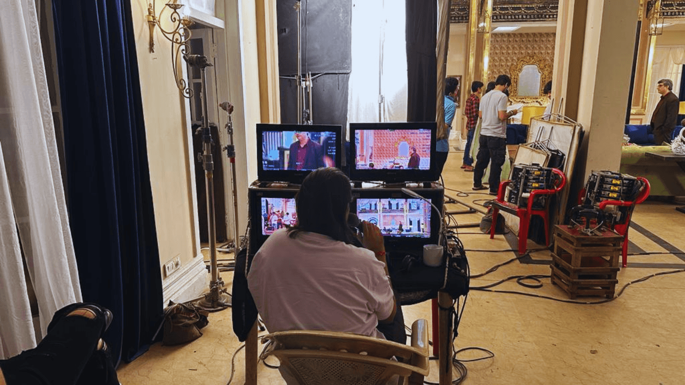 Film director monitoring live camera feeds during a Bollywood movie shoot inside a Mumbai studio