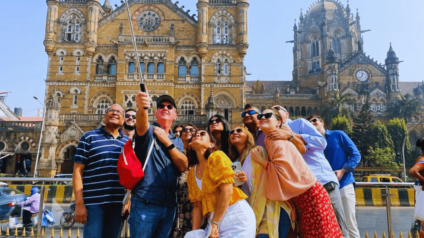 Tourists taking a group photo in front of Chhatrapati Shivaji Maharaj Terminus during a Mumbai city sightseeing tour