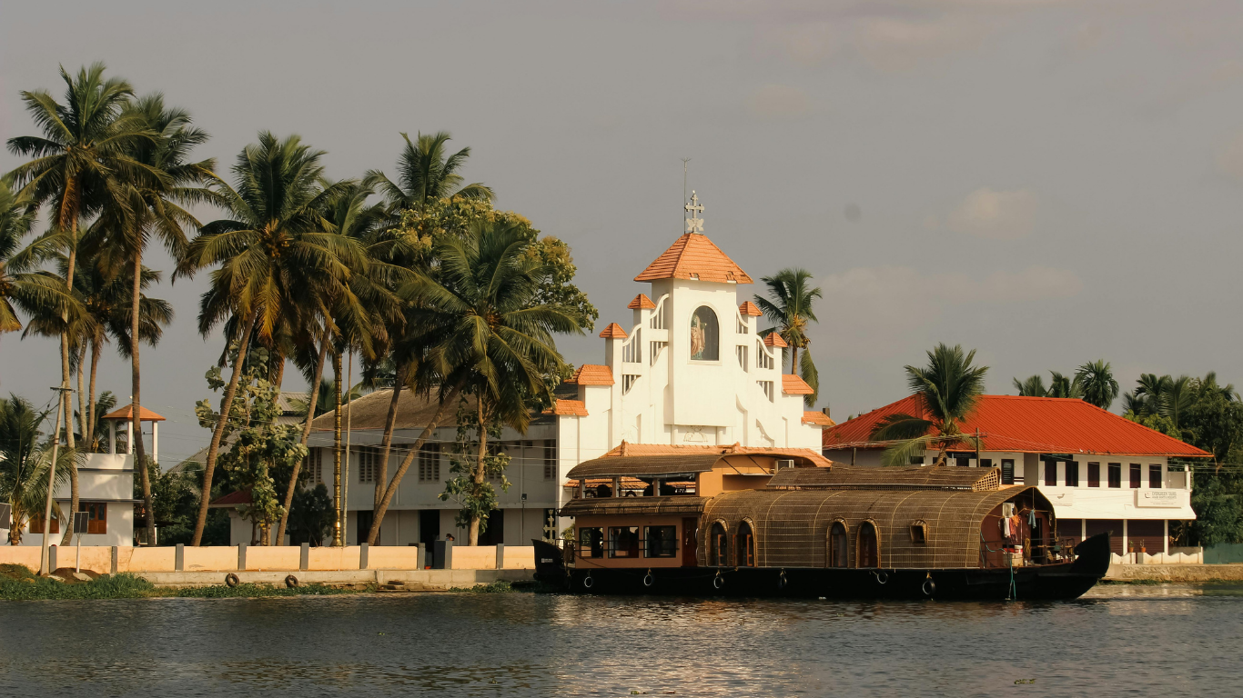 Portuguese-style church beside Goan backwaters with traditional houseboat