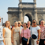 Independent shore excursions takes around a Group of international travelers posing together in front of the Gateway of India in Mumbai during a guided City Tour.