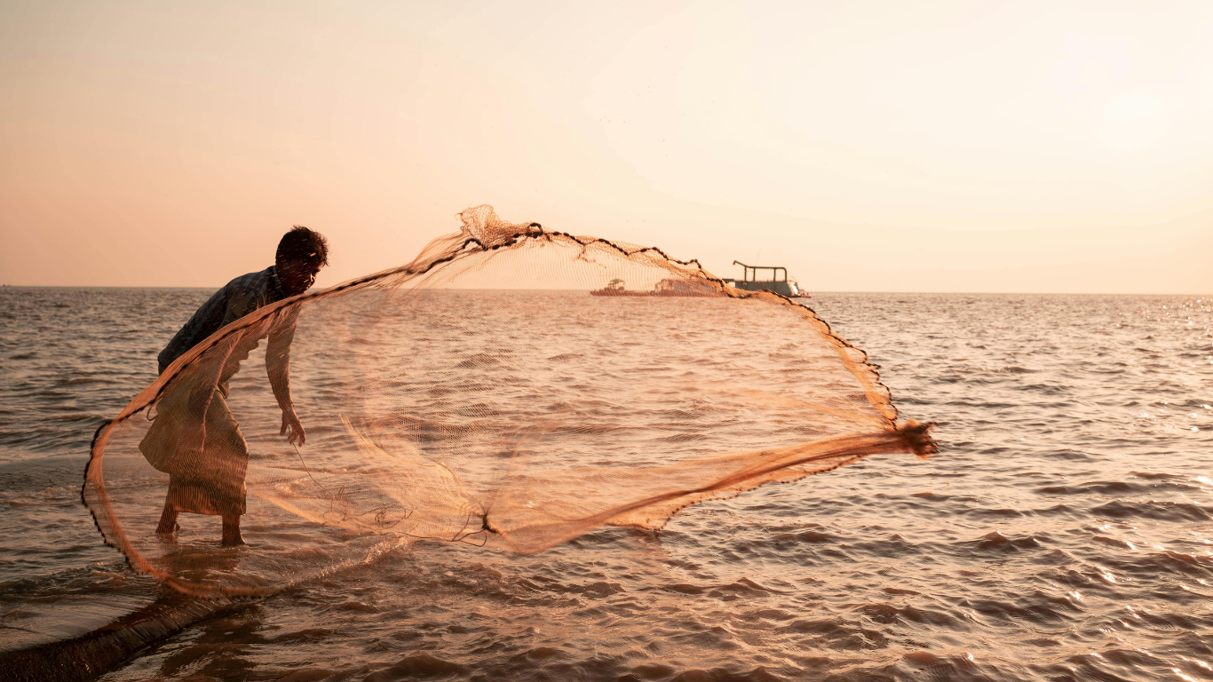 Local fisherman casting a net at sunset on the Goan coast